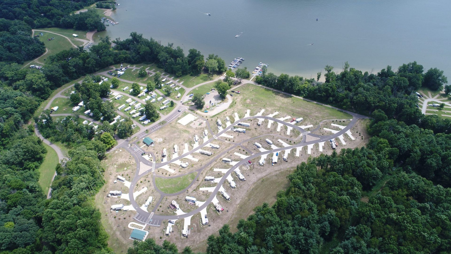 An aerial view of a campground surrounded by trees and a lake.