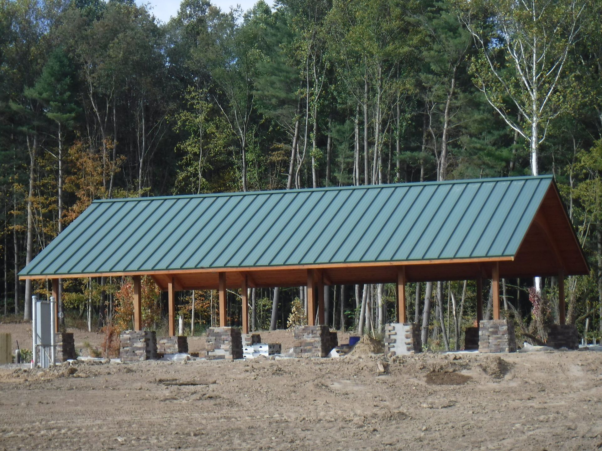 A wooden structure with a green roof in the middle of a field.