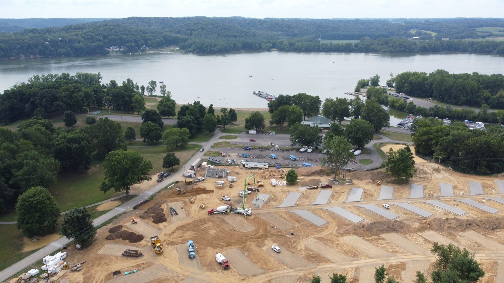 An aerial view of a construction site in a campground next to a lake.