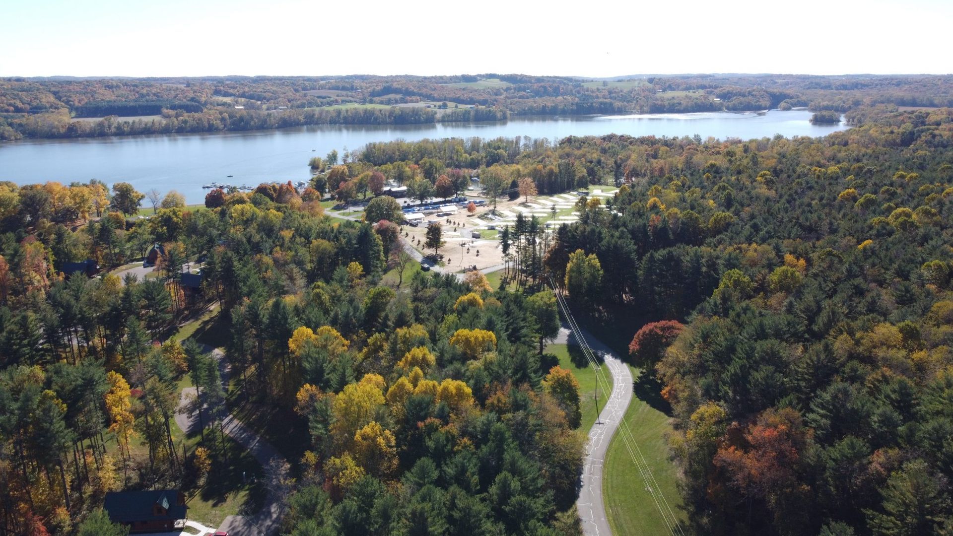 An aerial view of a lake surrounded by trees and a road.