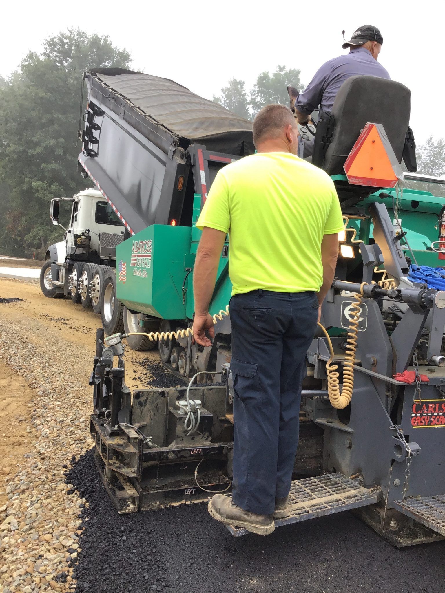 A man in a yellow shirt is standing next to a machine.