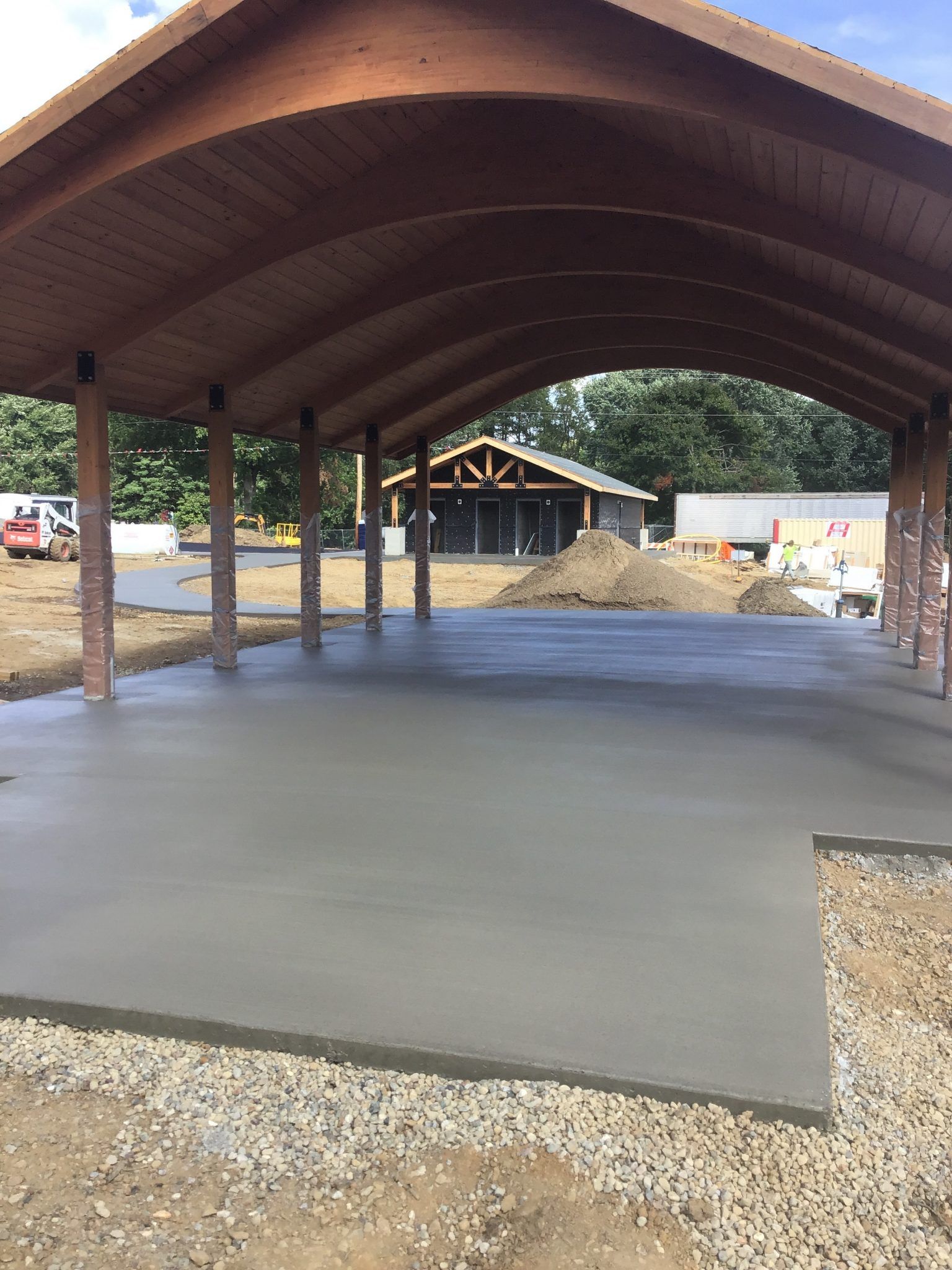 A concrete floor under a wooden roof in a parking lot.