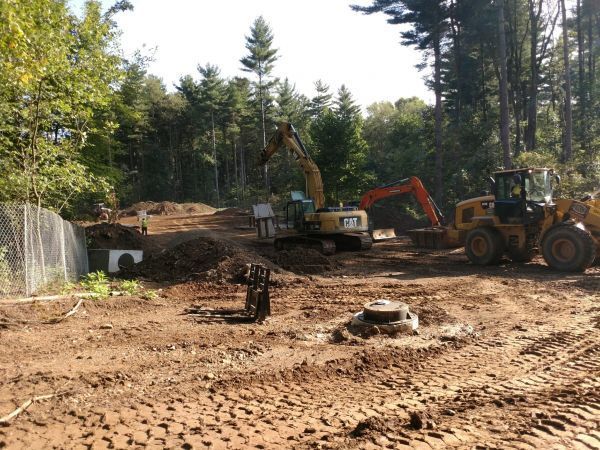 A cat excavator and a bulldozer are working in a dirt field.
