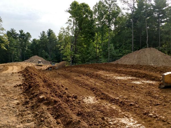 A construction site with a lot of dirt and trees in the background.