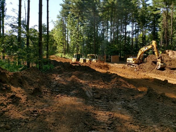 A construction site with a lot of dirt and trees in the background.