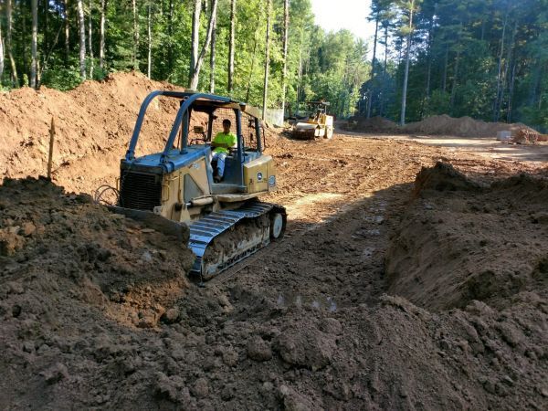 A man is driving a bulldozer on a construction site. 