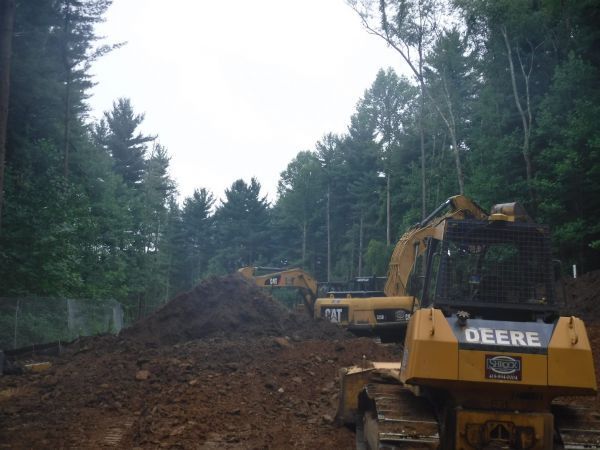 A Deere bulldozer is driving down a dirt road.