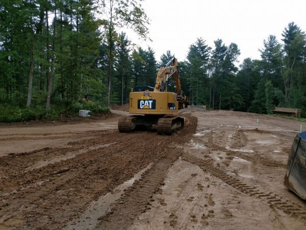 A cat excavator is driving down a muddy road.