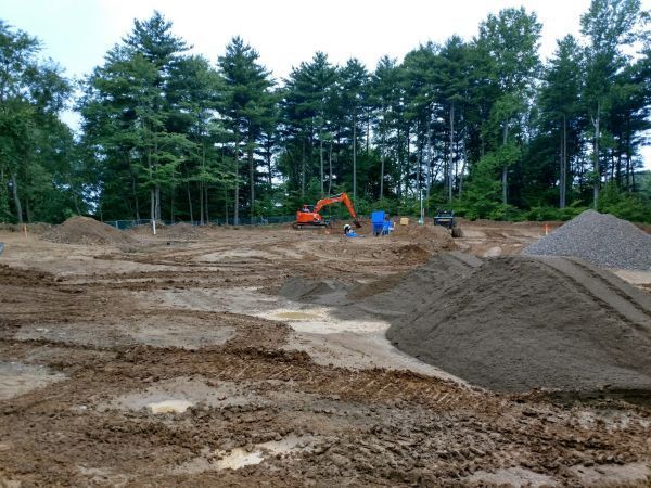 A large pile of dirt in a field with trees in the background.