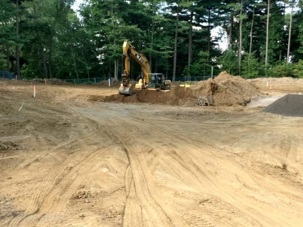 An excavator is digging a hole in a dirt field