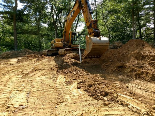 A large yellow excavator is digging a hole in the dirt.