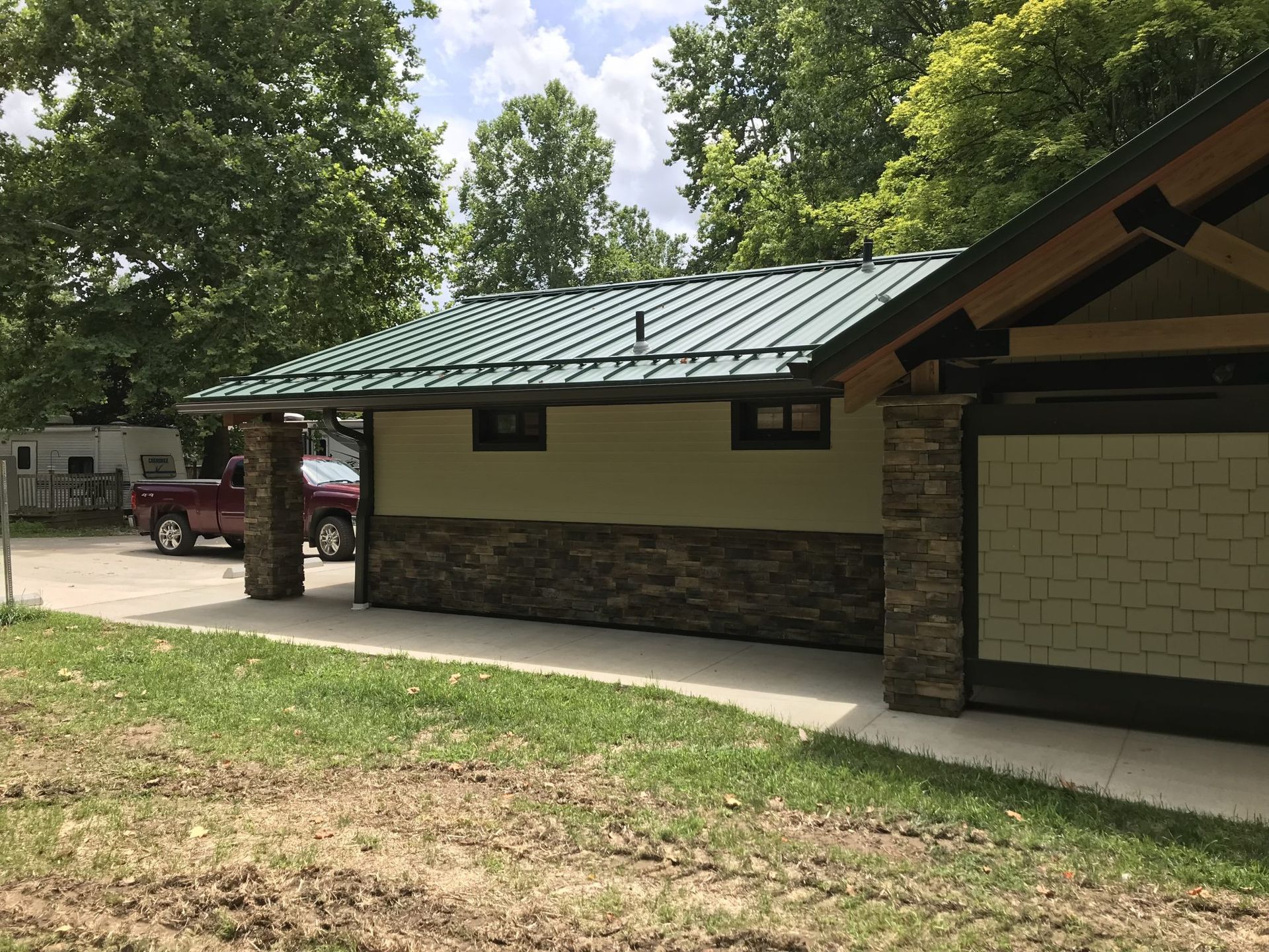 A small house with a green roof and a red truck parked in front of it.