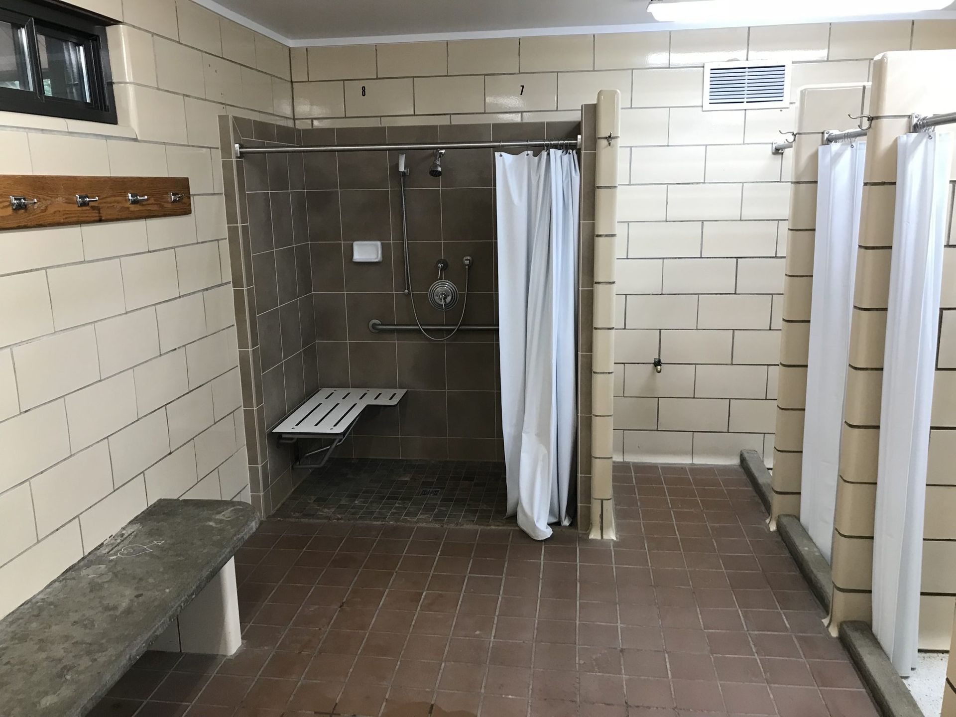 A bathroom with a shower stall and a bench