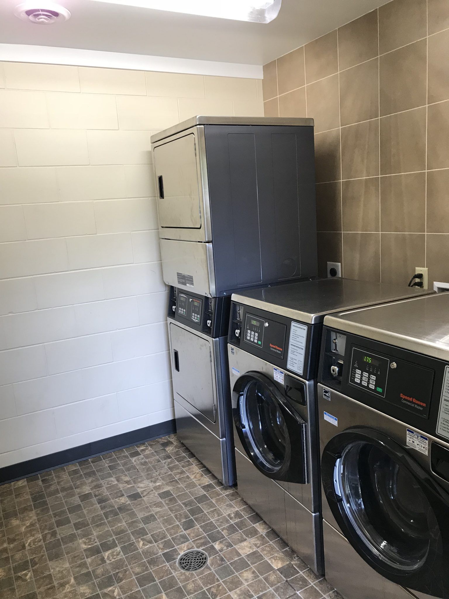 A laundry room with a stack of washing machines and dryers.