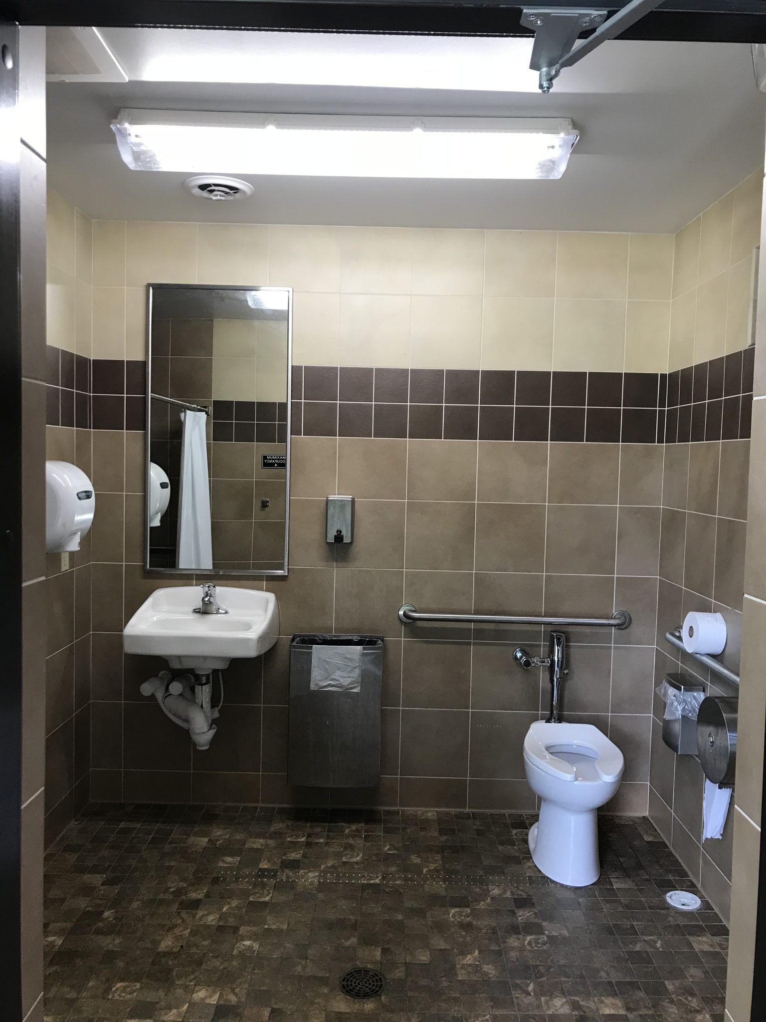 A bathroom with a toilet, sink, and mirror