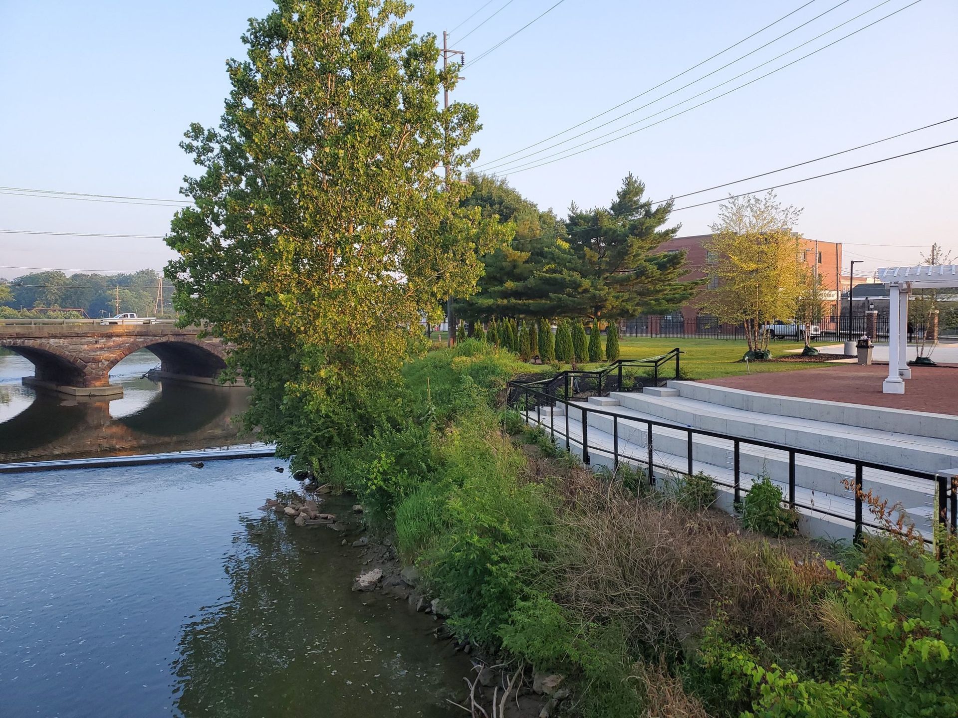A river with a bridge in the background and a park in the foreground.