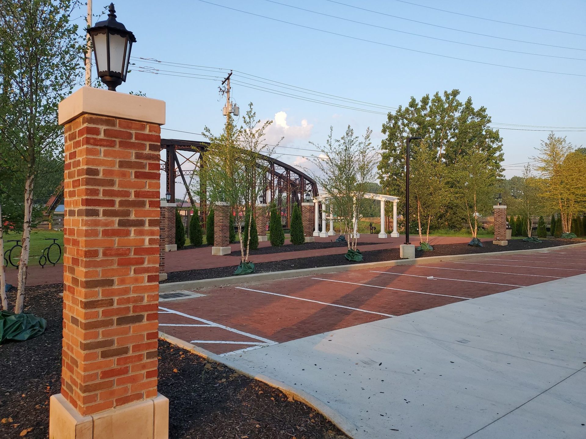 A brick pillar with a lamp on top of it and a bridge in the background.