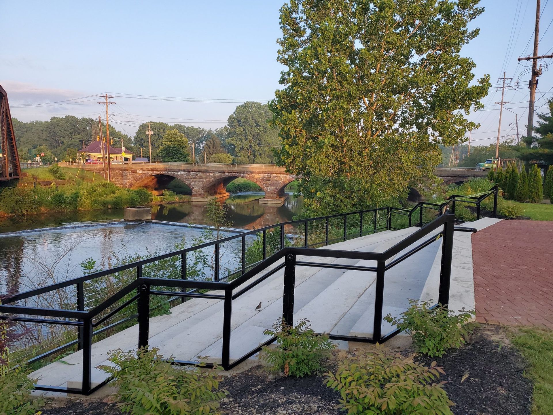 A ramp leading to a river with a bridge in the background.