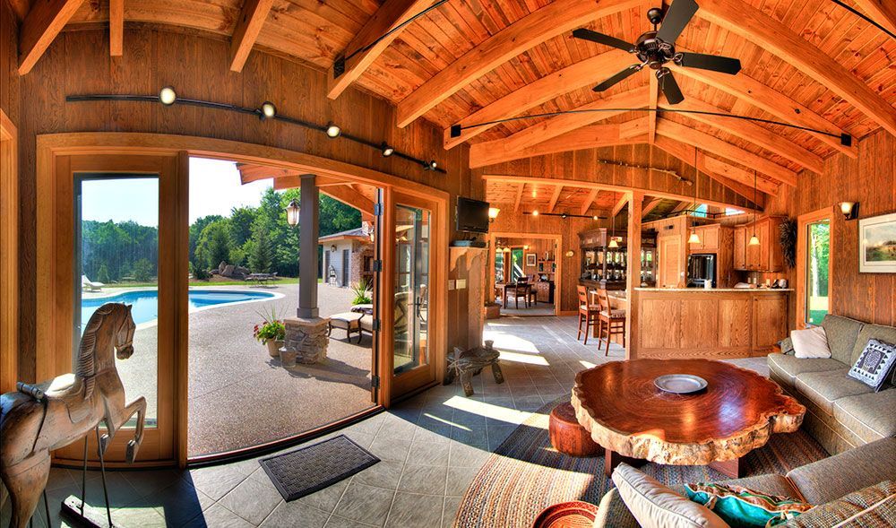 A custom pool house with a wooden table and a ceiling fan.