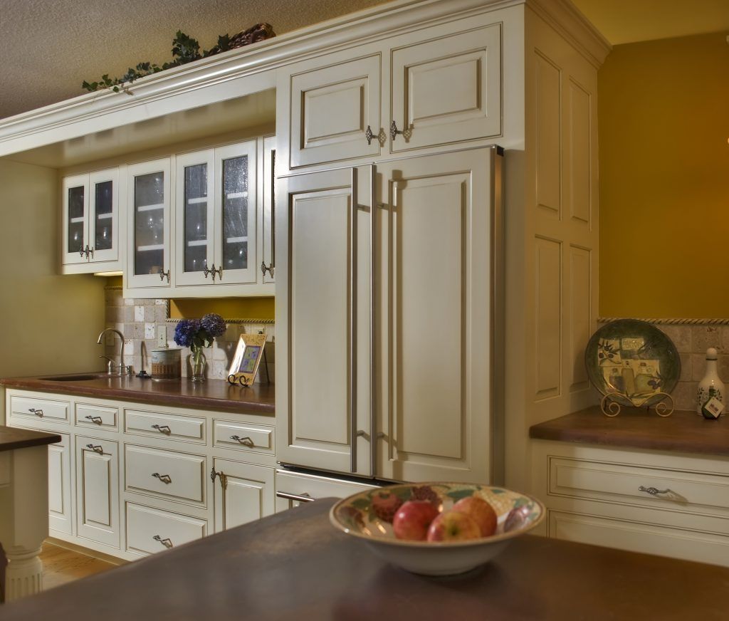 A kitchen with white cabinets and a bowl of fruit on the counter.