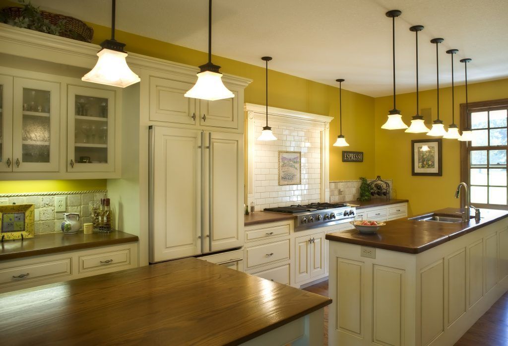 A kitchen with yellow walls and white cabinets.