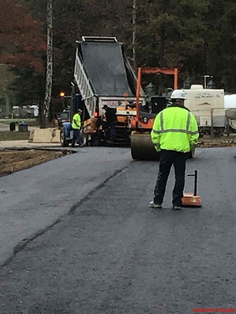 A man in a neon yellow jacket is standing in front of a dump truck.