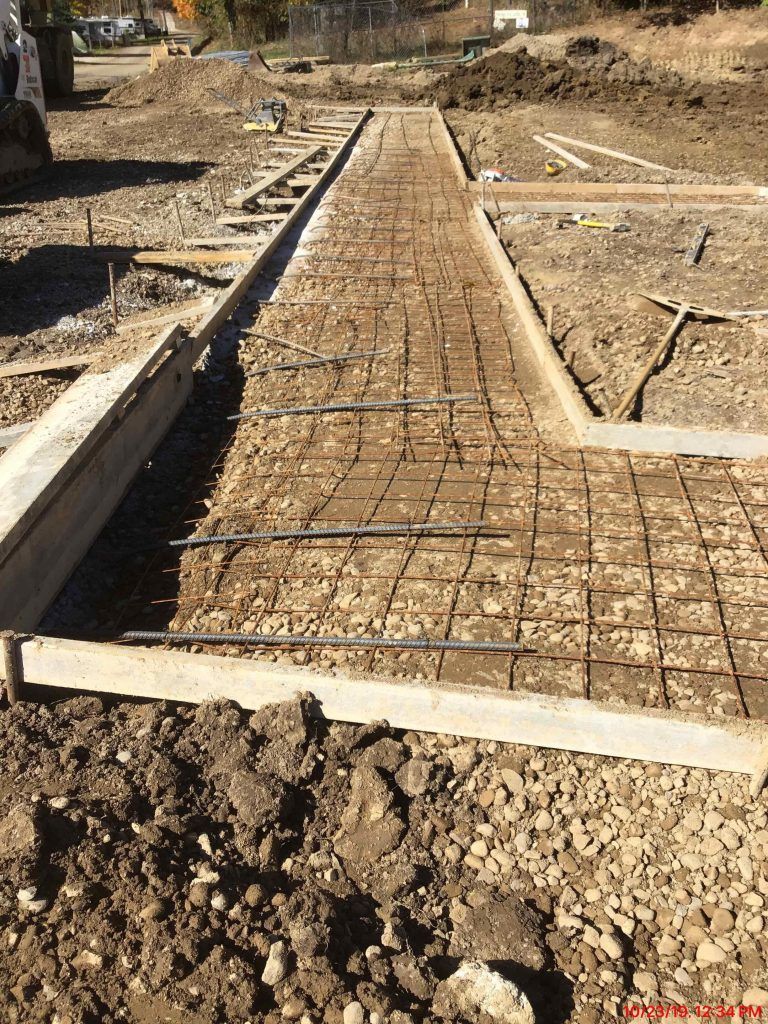 A concrete walkway is being built in a dirt field.