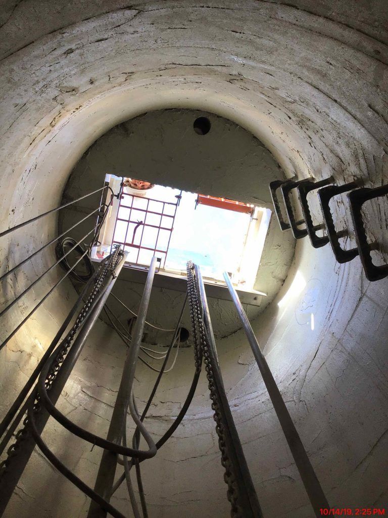 Looking up into a tunnel with a ladder and a window