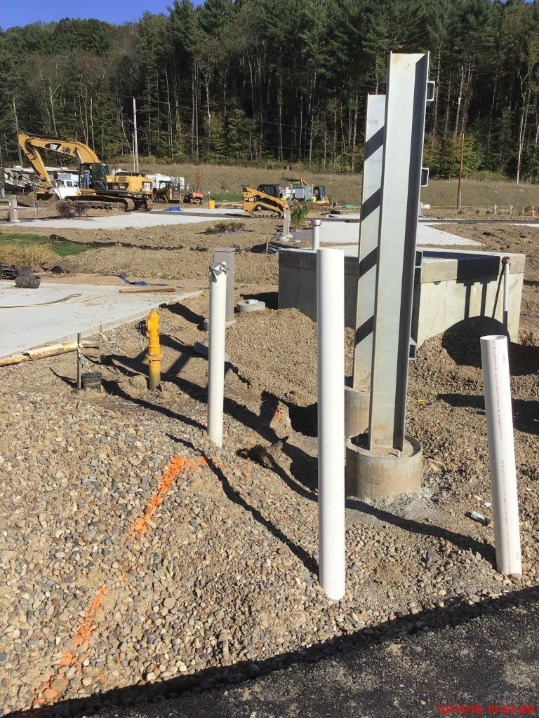 A construction site with a yellow excavator in the background.
