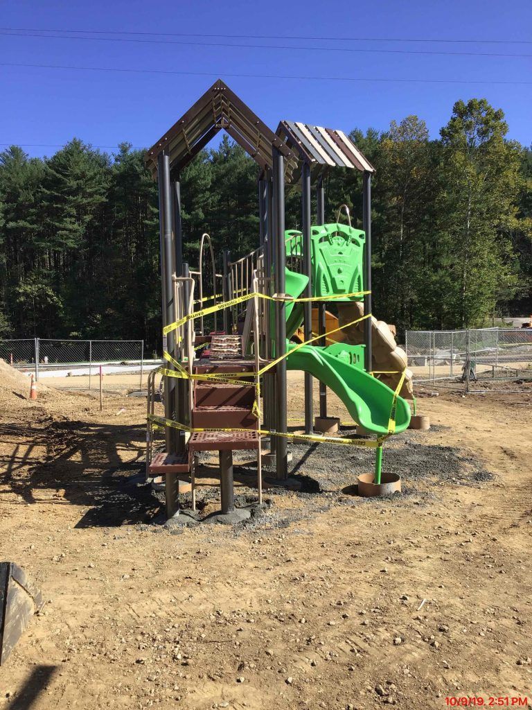 A playground is being built in the middle of a dirt field.