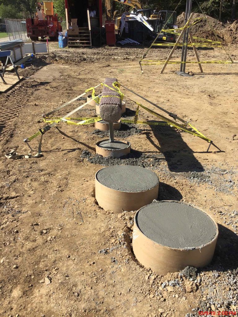 A group of concrete cylinders are sitting on top of a dirt field.