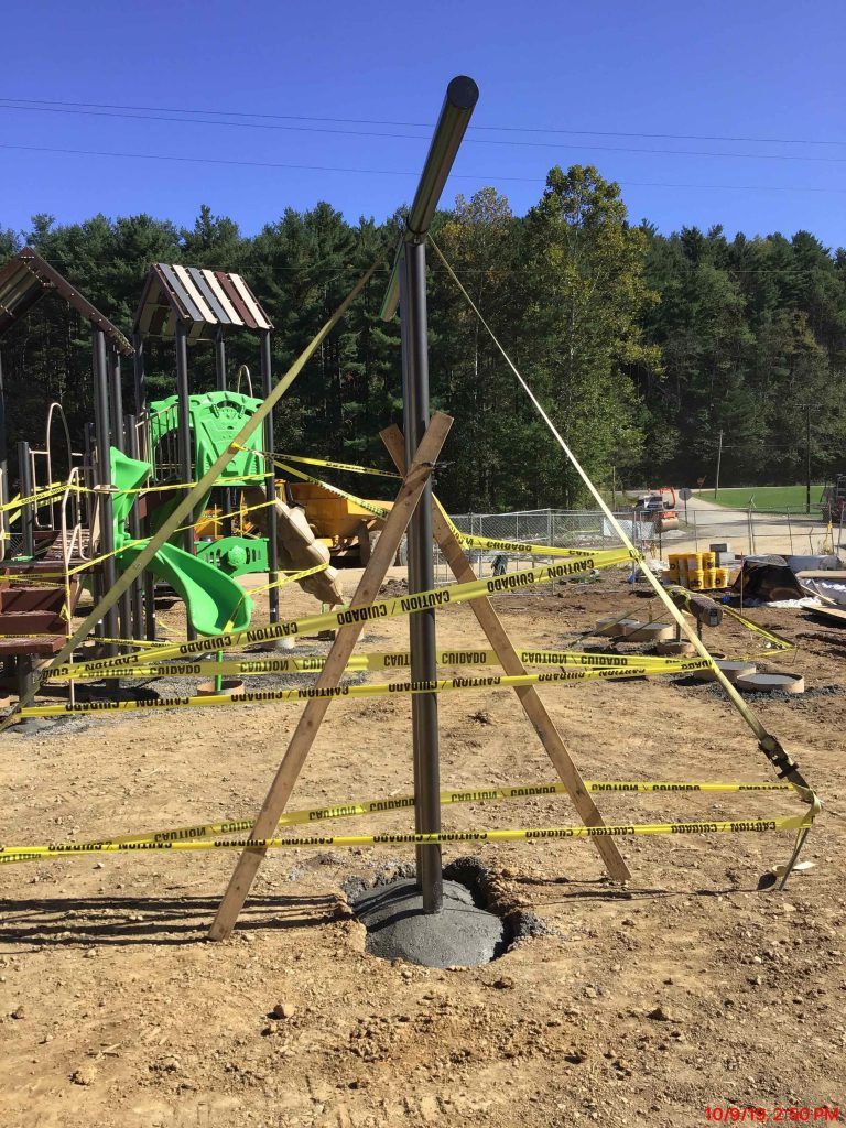 A playground is being built in the middle of a dirt field.