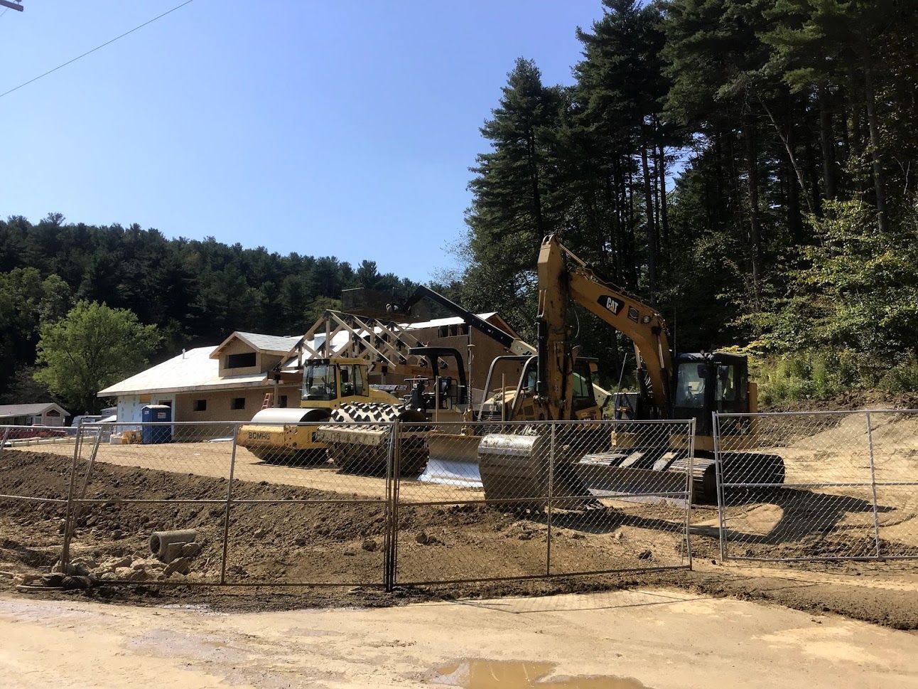 A construction site with a lot of machinery and a house in the background.