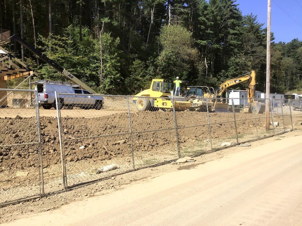 A truck is parked on the side of a dirt road next to a construction site.