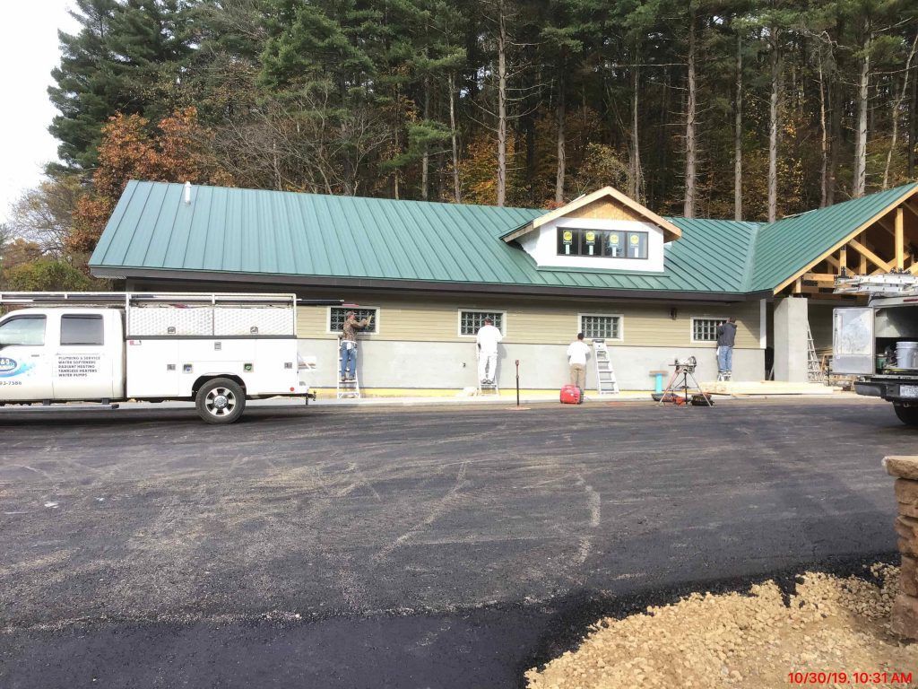 A white truck is parked in front of a building with a green roof.