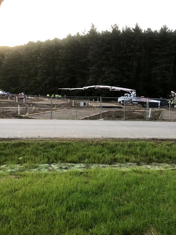A construction site with a lot of trucks parked on the side of the road.