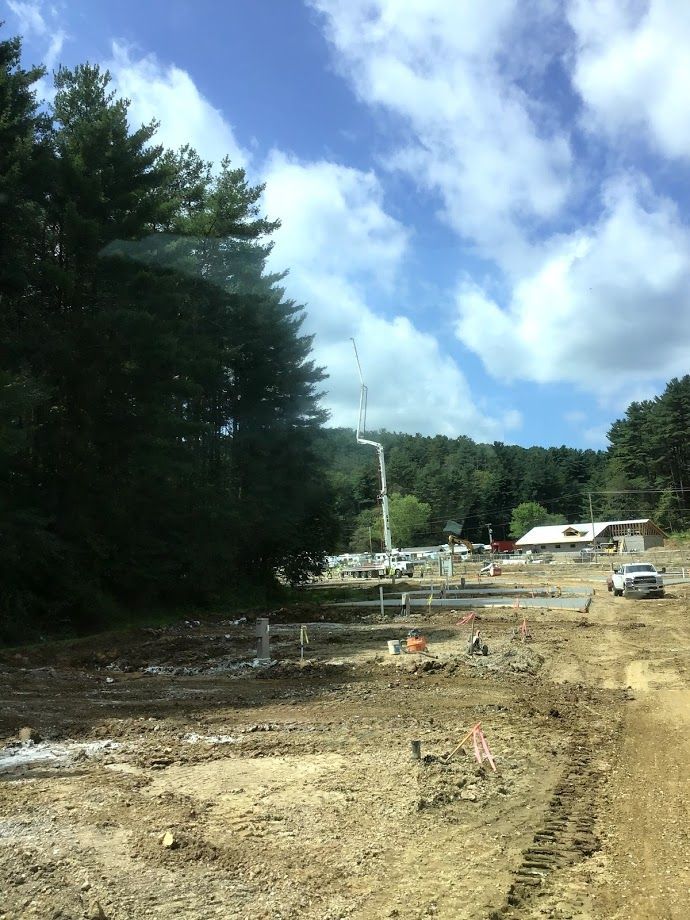 A construction site with a lot of dirt and trees in the background.