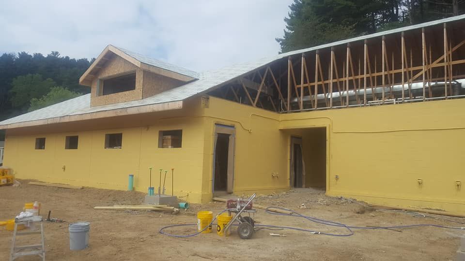 A large yellow building is being built in the middle of a dirt field.