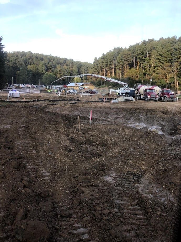 A construction site with a lot of dirt and trees in the background.