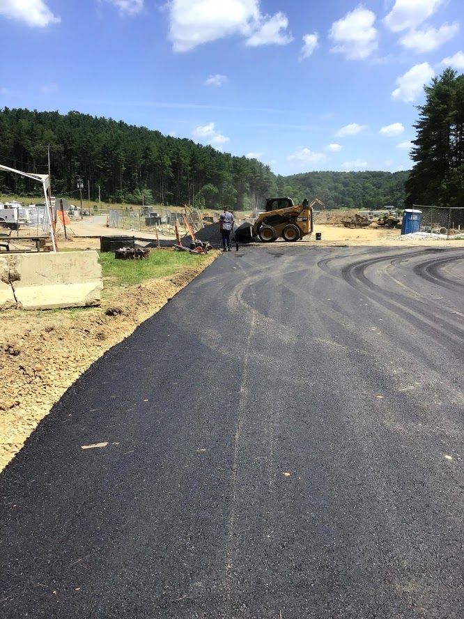 A man is standing on the side of a road next to a bulldozer.