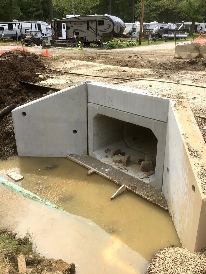 A concrete tunnel is being built in a muddy area.