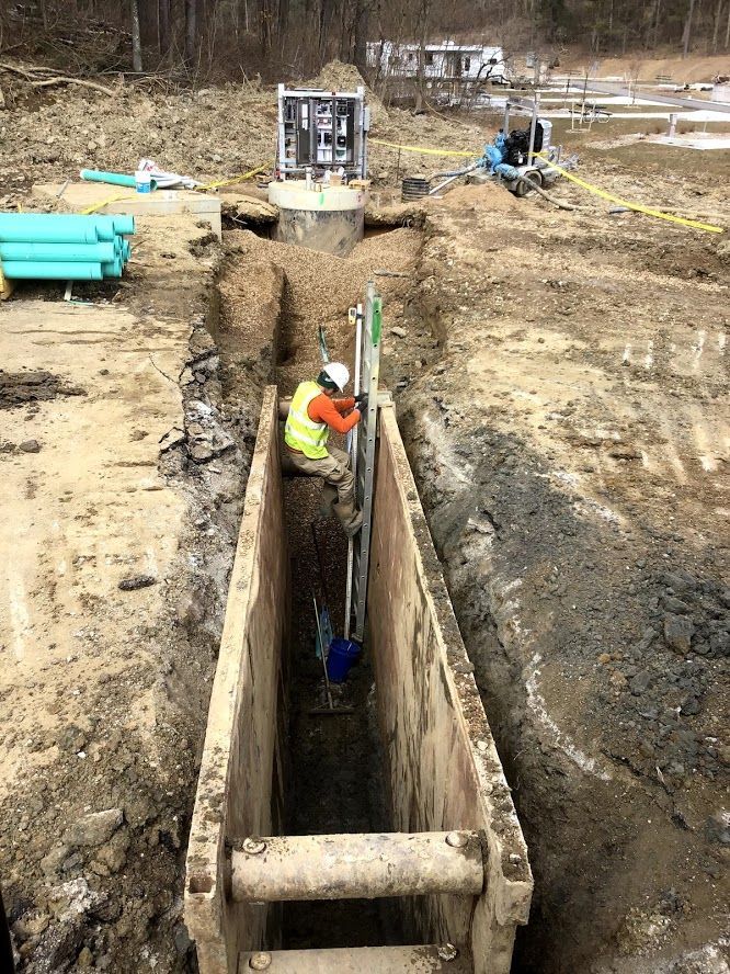 A man is working in a trench on a construction site.