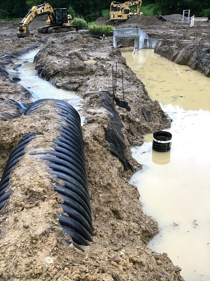 A large pipe is sitting in the middle of a muddy field.