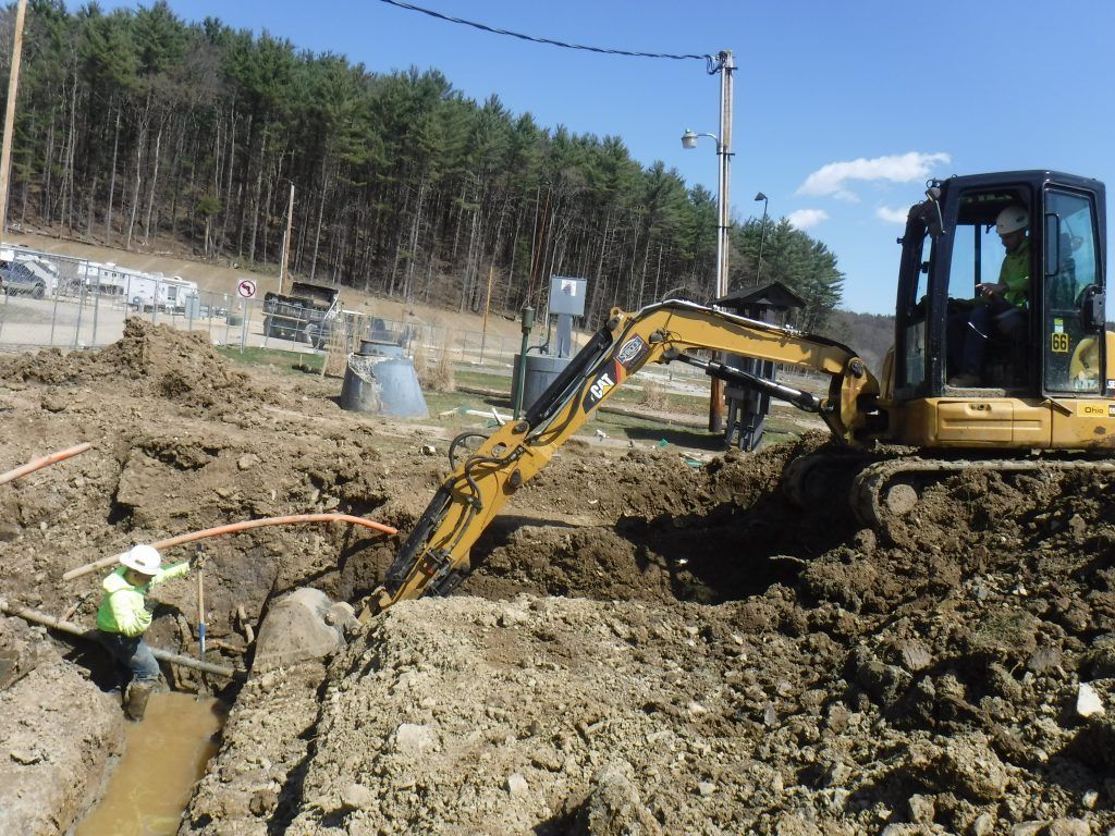 A man is digging a hole with an excavator in the background