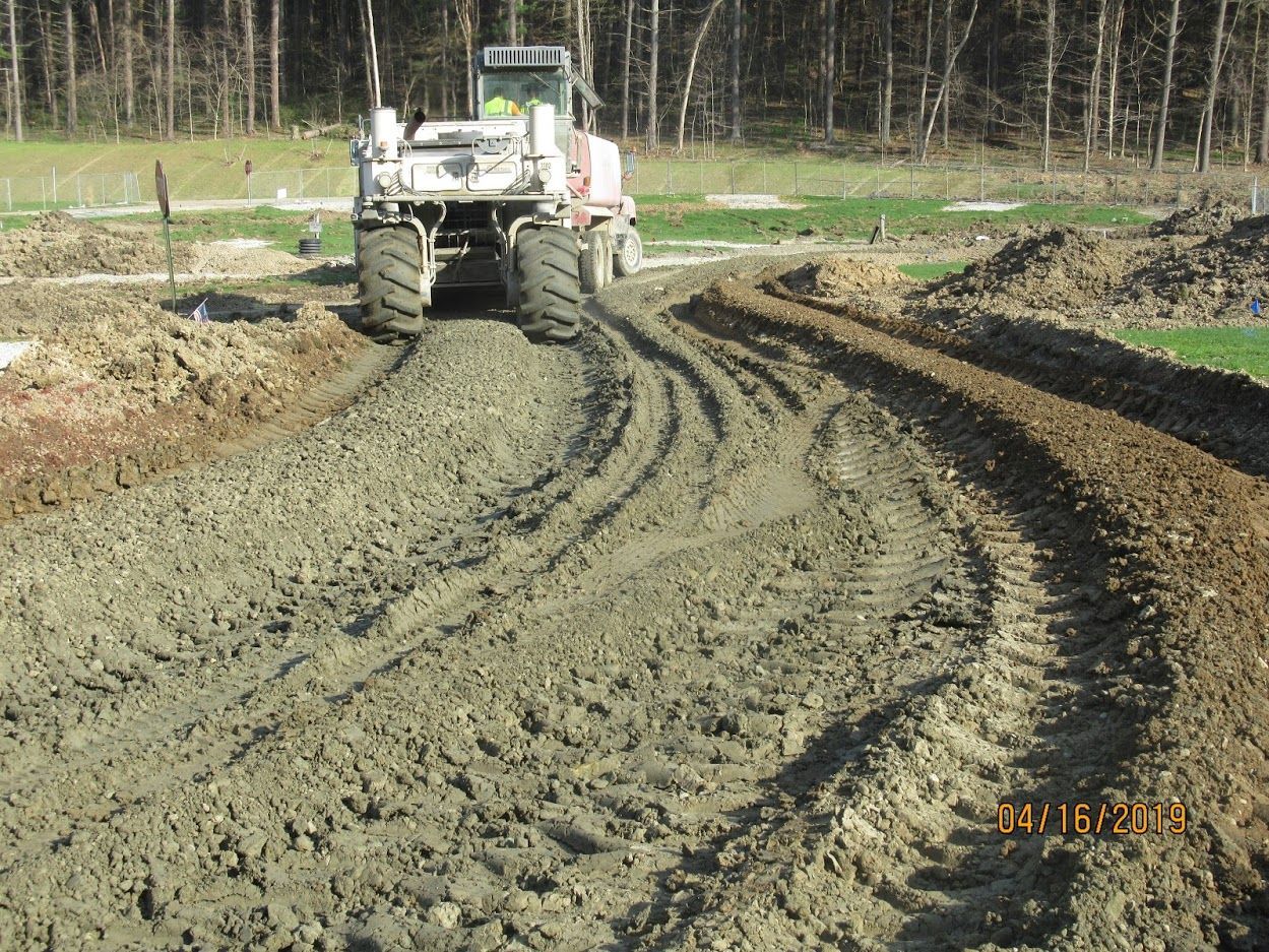 A tractor is driving down a dirt road.