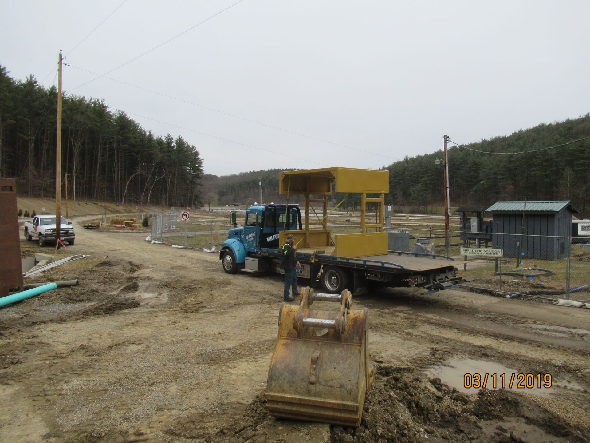 A blue truck is being towed by a yellow bulldozer