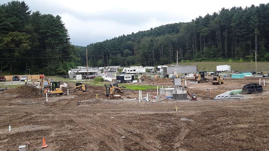 A construction site with a lot of machinery and trees in the background