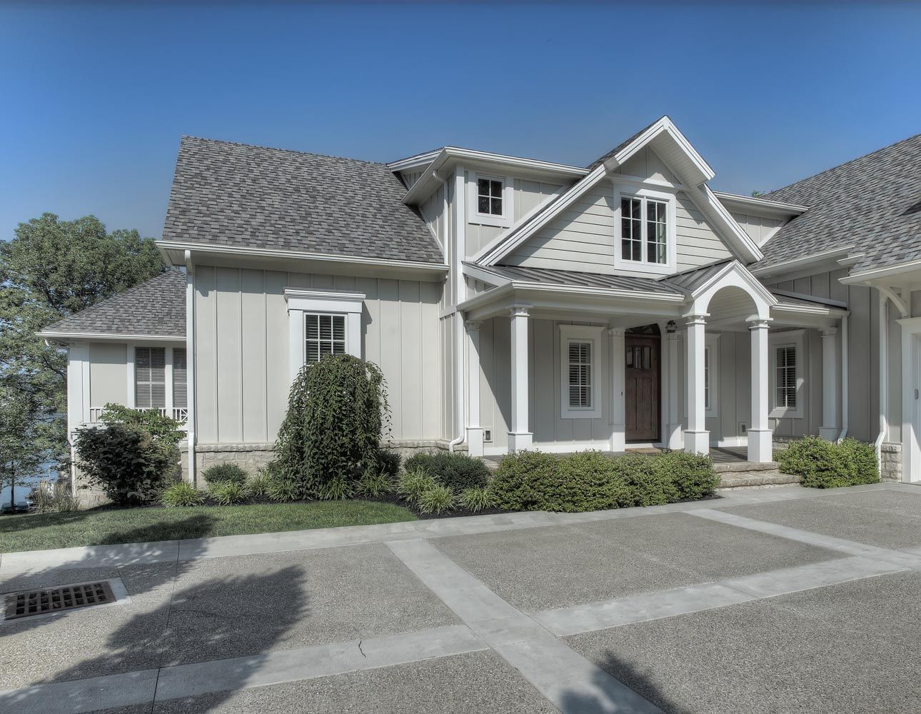 A large white house with a gray roof and a large driveway.