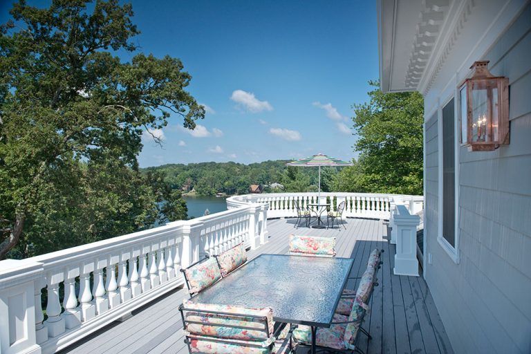 A large deck with a table and chairs overlooking a lake.