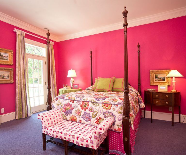 A bedroom with pink walls and a four poster bed.